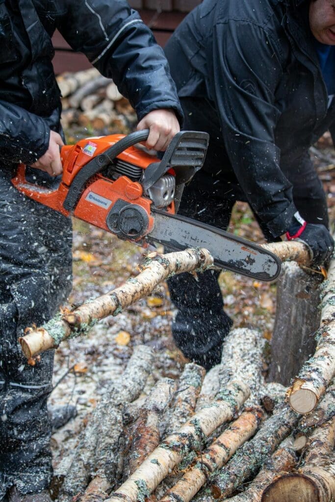 Chainsaw cutting a log during tree removal cleanup after a hazardous or damaged tree is taken down